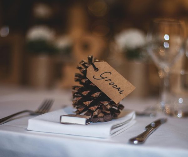 A beautifully arranged wedding table featuring a pine cone with a 'Groom' tag, adding rustic charm.